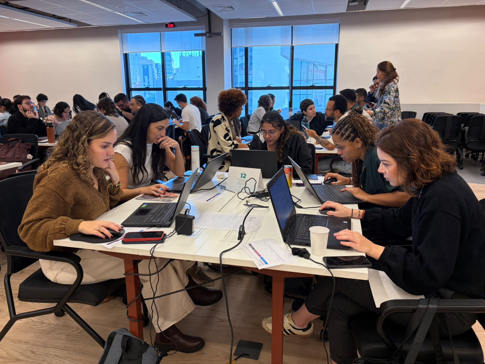 Um time de colaboradoras do Ismart trabalhando junto nos laptops durante o hackathon de IA
