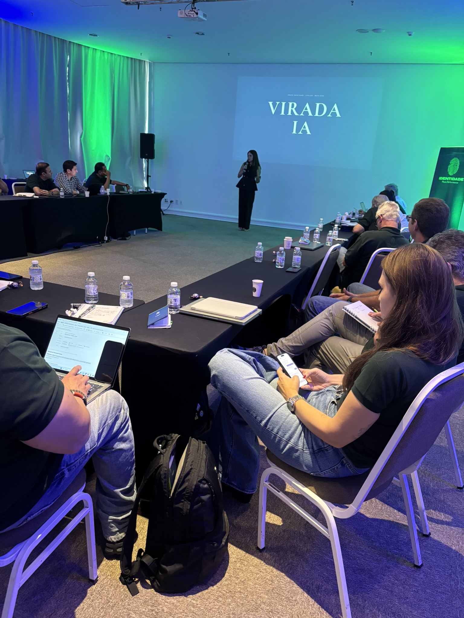 Bruna Santanna apresentando na Stoller com o slide Virada IA, em formato de mesa com a liderança